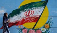An Iranian woman walks past a mural of the Iranian flag in the capital Tehran on October 14, 2017. (AFP) 