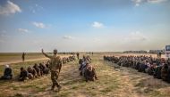 Men suspected of being Islamic State (IS) fighters wait to be searched by members of the Kurdish-led Syrian Democratic Forces (SDF) after leaving the IS group's last holdout of Baghouz, in Syria's northern Deir Ezzor province on February 22, 2019. / AFP /