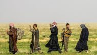 A fighter with the US-backed Syrian Democratic Forces (SDF) stands guard as people queue at a scanning area for those who are evacuated from the Islamic State (IS) group's embattled holdout of Baghouz, during an operation to expel IS jihadists from the ar
