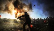 Palestinian throws a stone with a slingshot towards Israeli security forces during the 