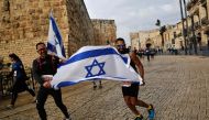 Competitors hold the Israeli flag along the Old City ramparts during Jerusalem's 9th International Marathon, on March 15, 2019. AFP / Gil Cohen-Magen 