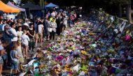 Floral tributes to those who were gunned down at the two mosques are seen against a wall bordering the Botanical Garden in Christchurch on March 19, 2019.   AFP / Marty MELVILLE