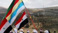 Druze community members holds Syrian and Druze flags as they sit facing Syria, during a rally marking the anniversary of Israel's annexation of the Golan Heights in the Druze village of Majdal Shams in Golan Heights February 14, 2019. Reuters/Ammar Awad 