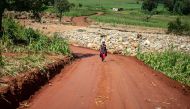 A woman walks on a road near a damaged bridge in Chimanimani as efforts to restore damaged road transport services are intensified, on March 22, 2019. AFP / Zinyange AUNTONY