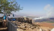 FILE PHOTO:  Members of the United Nations Disengagement Observer Force Zone (UNDOF) using a binocular to look towards the Syrian side of the Golan Heights as smoke billows during clashes between forces loyal to Syrian President Bashar Assad and rebels ov