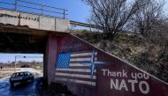 A car drives past a graffiti reading 'Thank You Nato' and featuring the US flag near the village of Stagovo on March 24, 2019. AFP / Armend NIMANI