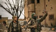 Members of the Syrian Democratic Forces (SDF) use a cell phone to take a 