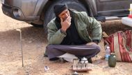 Milad Mohamad, a Truffle hunter, smokes a cigarette at a camp site during a search for white truffles, known locally as 