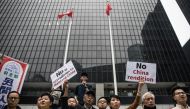 Hong Kong pro-democracy legislator Claudia Mo (centre R) and bookseller Lam Wing-kee (centre L) display placards outside the government headquarters during a rally in Hong Kong on March 31, 2019 to protest against the government's plans to approve extradi