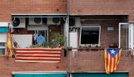 A woman hangs a Catalan flag next to a Spanish flag on her balcony, next to an Estelada (Pro-independence Catalan flag) hanging from a neighbor's balcony in Barcelona on September 25, 2017.  AFP/Pau Barrena