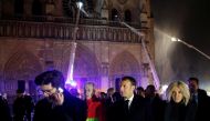 French President Emmanuel Macron and his wife Brigitte walk outside the Notre Dame Cathedral where a fire continues to burn in Paris on April 16, 2019.  AFP / Pool / Philippe Wojazer 