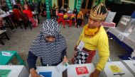 An electoral official wearing a costume of a wayang character stands as a voter marks her ballots at a polling center in Yogyakarta, Indonesia, April 17, 2019 REUTERS/Dwi Oblo