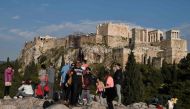 Tourists take selfies in front of the ancient Acropolis after it was closed following a lightning storm injuring four people on April 17, 2019.   AFP / LOUISA GOULIAMAKI