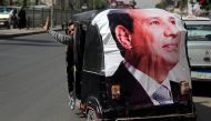 A man gestures as he rides a motorized vehicle showing a poster of Egyptian President Abdel Fattah al-Sisi in Cairo, Egypt, March 27, 2018. Reuters/Ammar Awad