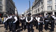 Police officers keep watch as climate change activists continue to block the road at Oxford Circus in London on April 20, 2019, on the sixth day of an environmental protest by the Extinction Rebellion group after police towed away the pink boat being used