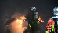 Firefighters extinguish burning scooters and motorbikes set on fire during an anti-government demonstration called by the 