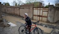 Afghan cyclist Kobra Samim adjusts her bicycle on a street in Kabul. / AFP / Wakil Kohsar 