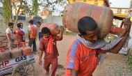 In this photograph taken on April 9, 2019, Indian liquid petroleum gas (LPG) vendors carry gas cylinders at a distribution centre in Patna. AFP / NARINDER NANU 