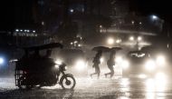 People cross a road during heavy rain caused by Typhoon Maliksi in Manila on June 10, 2018. AFP/Noel Celis