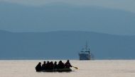 Migrants in a dinghy paddle their way on the Mediterranean Sea to attempt crossing to the Greek island of Kos, as a Turkish Coast Guard ship patrols off the shores off Bodrum, Turkey, September 19, 2015. Reuters/Umit Bektas