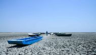 In this picture taken on June 4, 2019, an Indian boatman walks amid boats on the dried bed of a lake at Nalsarovar Bird Sanctuary, on the eve of World Environment Day. AFP / Sam Panthaky 