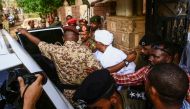 Sudan's ousted president Omar al-Bashir (C) is escorted into a vehicle as he returns to prison following his appearance before prosecutors over charges of corruption and illegal possession of foreign currency, in the capital Khartoum on June 16, 2019. / A