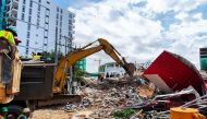 Rescue workers use an earthmover to clear debris after an under-construction building collapsed in Sihanoukville on June 22, 2019. / AFP / Ly LAY 