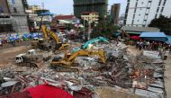 Rescue workers use earthmovers to clear debris as they search for victims a day after an under-construction building collapsed in Sihanoukville on June 23, 2019. AFP / Sun Rethy Kun