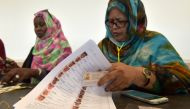 An election official checks for a voter name on the electoral list at a polling station on June 22, 2019, in Nouakchott during Mauritania's presidential election. AFP / Sia KAMBOU