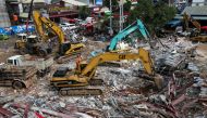 Rescue workers use earthmovers to clear debris as they search for victims a day after an under-construction building collapsed in Sihanoukville on June 23, 2019.   AFP / SUN RETHY Kun