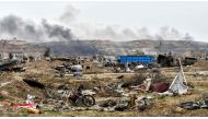 In this file photo taken on March 24, 2019, smoke rises behind destroyed vehicles and damaged buildings in the village of Baghouz in Syria's eastern Deir Ezzor province near the Iraqi border, a day after the Islamic State (IS) group's 
