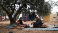In this file photo taken on June 04, 2019, an elderly Syrian couple sits under an olive tree at a DIP camp for Interally Displaced Persons near the town of Aqrabat in Syria's northern Idlib province, as Muslims around the world celebrate Eid al-Fitr, the 