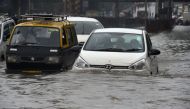 Vehicles drive along a flooded street after heavy rain showers in Mumbai on July 1, 2019. / AFP / PUNIT PARANJPE 