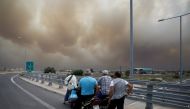 FILE PHOTO: People look at smoke as a wildfire burns in Kineta near Athens, Greece, July 23, 2018. Reuters/Alkis Konstantinidis