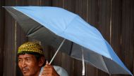 A street vendor uses an umbrella as he waits for customers at a traditional market in Jakarta, Indonesia, June 3, 2019. Reuters/Willy Kurniawan