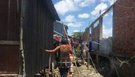 A woman walks on a makeshift bridge of wooden planks and poles in an informal settlement at the edge of Boeung Tompoun, Phnom Penh, Cambodia. May 27, 2019. Thomson Reuters Foundation/Rina Chandran