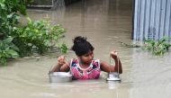 An Indian girl carries drinking water as she wades through flood waters at Pabhokathi village in Morigaon district of India's Assam state on July 15, 2019. AFP / Biju Boro 