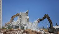 This picture taken from Jerusalem on July 22, 2019 shows Israeli security forces tearing down one of the Palestinian buildings still under construction which have been issued notices to be demolished in the West Bank village of Dar Salah, adjacent to the 