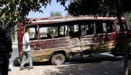A boy walks past the wreckage of a bus following a suicide bombing in Kabul on July 25, 2019. (AFP)