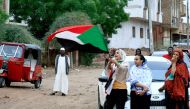 Sudanese demonstraters wave their national flag as they celebrate in Khartoum early on August 3, 2019, after Sudan's ruling generals and protest leaders reached a 
