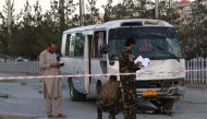 Afghan security personnel investigate a damage bus carrying employees of Khurshid TV, at the site of a sticky bomb blast in Kabul on August 4, 2019.   AFP / STR