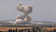 Smoke billows above buildings during a reported air strike by pro-regime forces near the town of Hish in Syria's Idlib province on August 19, 2019.