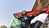 A Sudanese man spreads a national flag in Omdurman as he takes part in a rally in solidarity with Ahmed al-Kheir, a young Sudanese who died in custody after his arrest in January on allegations of organising anti-Bashir protests, on August 28, 2019.  AFP 