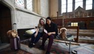 Andrea Stewart (L) and Kae Ono sit with Coco the dog as they settle in at St Mary's Church, where guests can pay to stay overnight in what is known as 'champing', in Edlesborough, Buckinghamshire on September 2, 2019.  AFP / Glyn Kirk 
