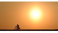 A cyclist passes a street near the village of Pflaumdorf, southern Germany during sunset on February 28, 2019. AFP/Christof Stache