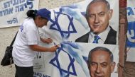 A woman places electoral banners for the Likud party showing Benjamin Netanyahu in the southern Israeli city of Beersheva on September 15, 2019. AFP/Hazem Bader
