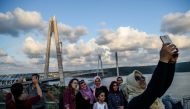 People take selfies as they pose next to the Yavuz Sultan Selim bridge on August 26, 2016, in Istanbul during the inauguration of the bridge. AFP