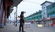 A security personnel stands guard to block a road near closed shops while strict restrictions are imposed during a lockdown in Srinagar on September 28, 2019. / AFP / Tauseef MUSTAFA