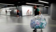 A worker walks as he holds a big plastic bag full of plastic bottles in San Giovanni metro station in Rome, Italy September 27, 2019. Reuters/Remo Casilli
