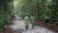 Two forest rangers walk on a road in the Akanda forest, a national park a few kilometers from the city centre of the capital, Libreville on September 27, 2019.  AFP / Steve Jordan 